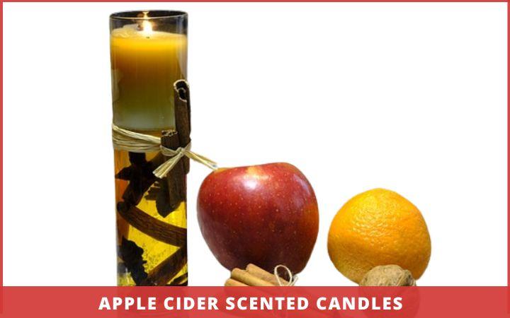 apple cider scented candle with an apple and orange at the side