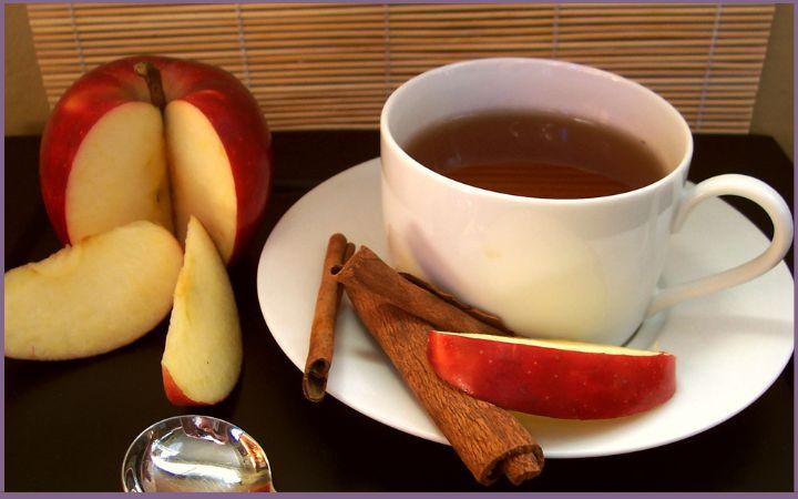 cup of cinnamon tea with apple slices and cinnamon sticks