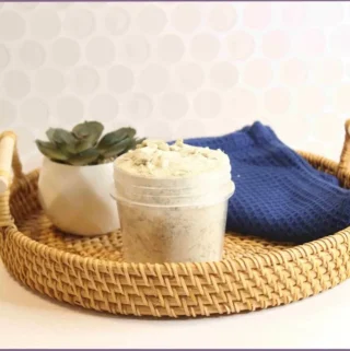 Homemade bentonite clay detox bath in a rattan basket with face towel and succulent in a vase