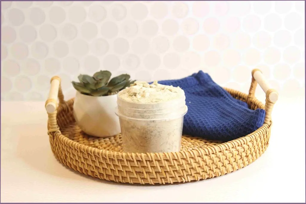 Homemade bentonite clay detox bath in a rattan basket with face towel and succulent in a vase