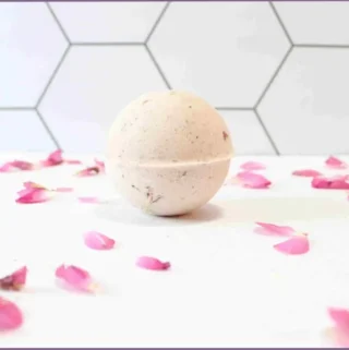 Homemade bath bomb surrounded by pink rose petals