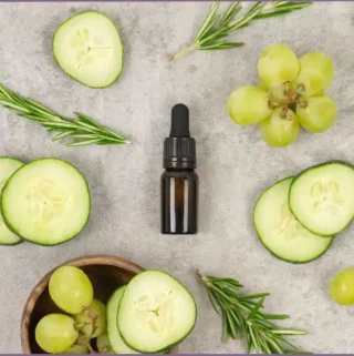 essential oil bottle surrounded by cucumber slices and grapes - cooling essential oil
