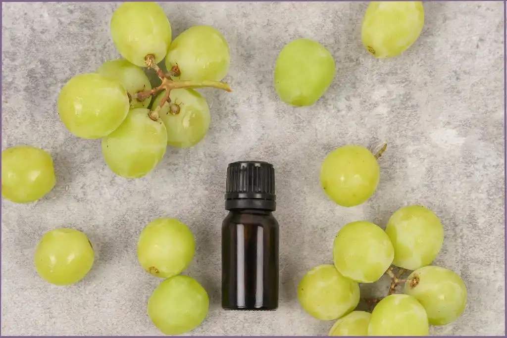 essential oil bottle surrounded by green grapes