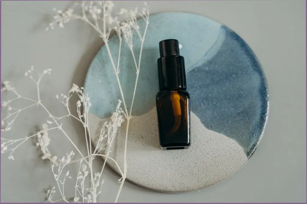 essential oil bottle with spray top on blue ceramic plate