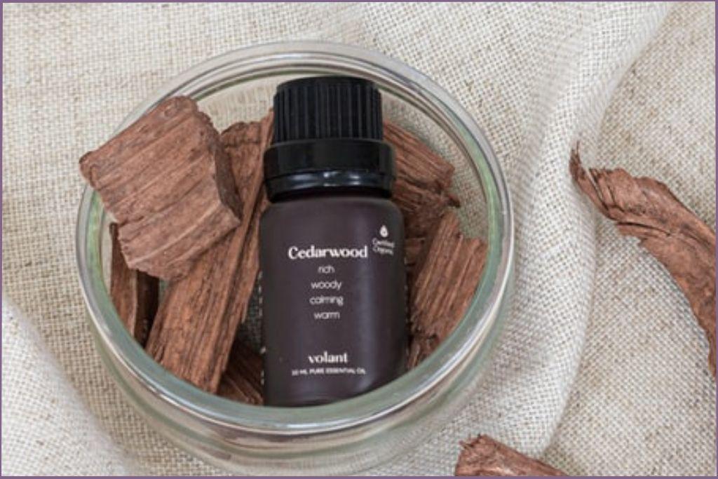 bottle of cedarwood essential oil lying on top of cedarwood chips