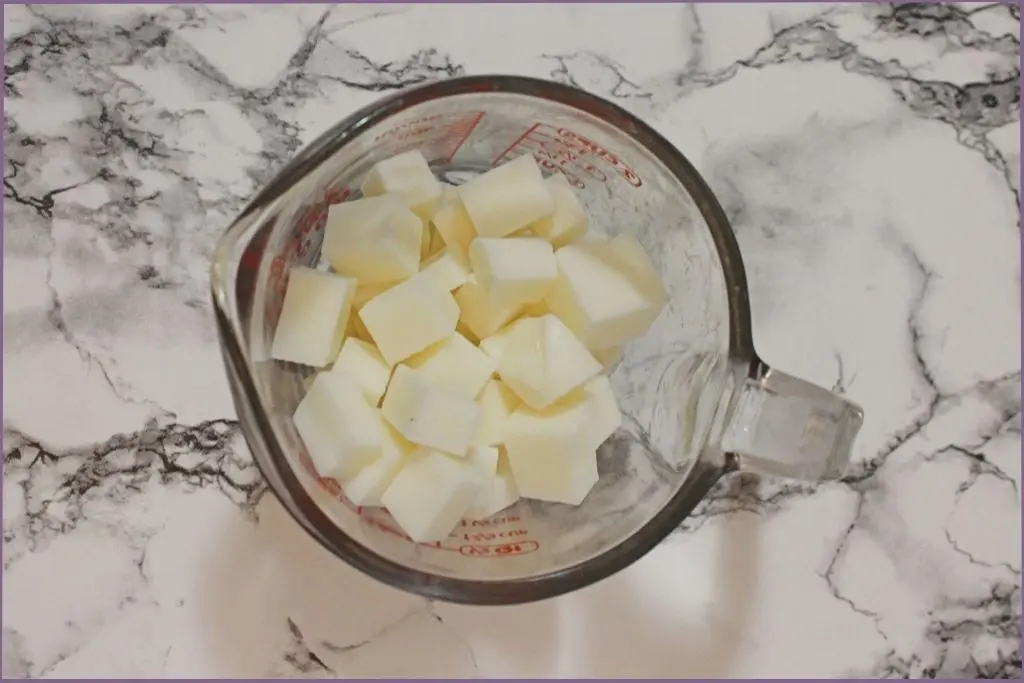 glass measuring jar with pieces of shea butter soap pieces for making melt and pour soap