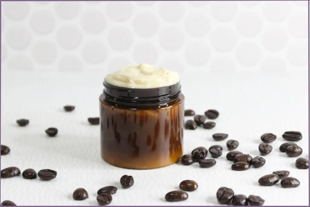 homemade coffee eye cream in amber glass jar with coffee beans scattered around table