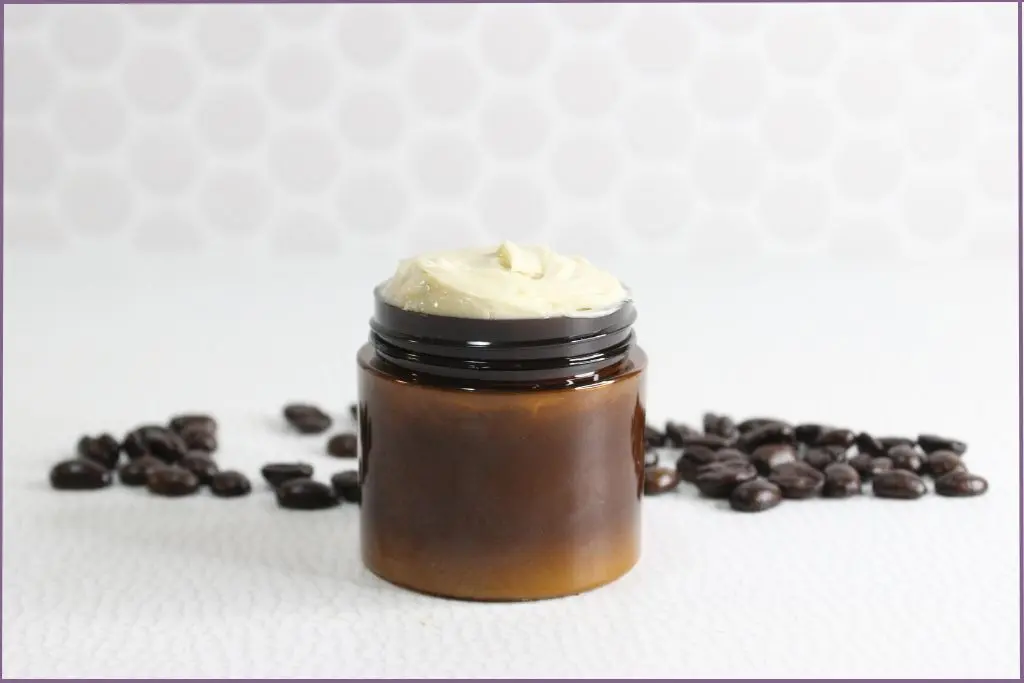 homemade coffee eye cream in amber glass jar with coffee beans scattered around table