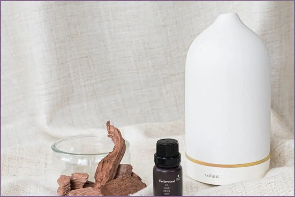 bottle of cedarwood essential oil alongside a diffuser