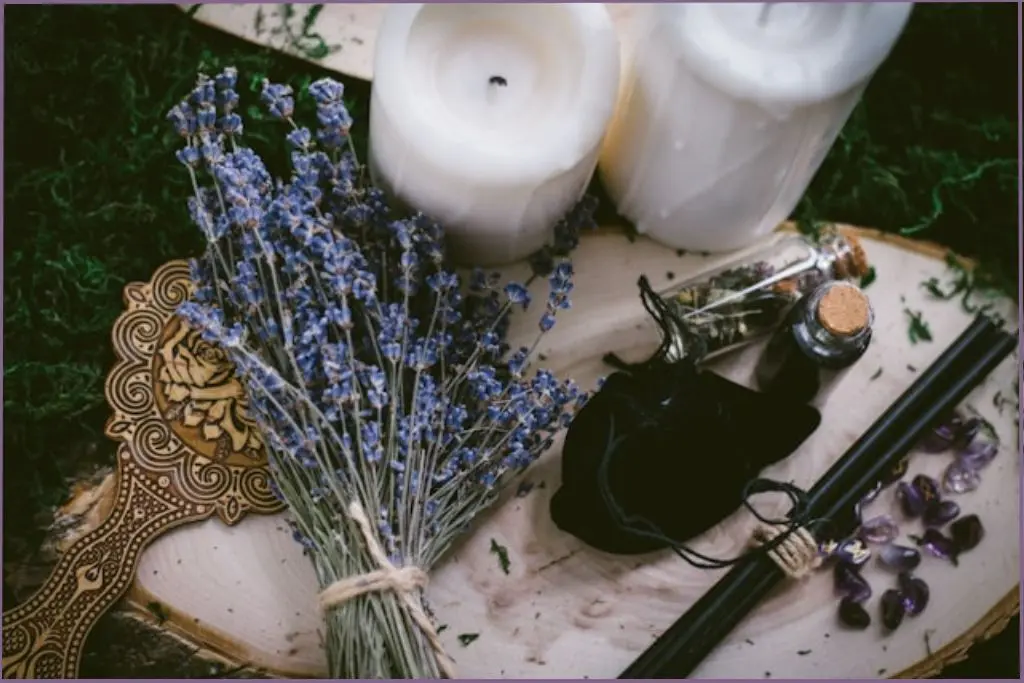 small table with candles, lavender flowers, 2 bottles with herbs and 2 black wands