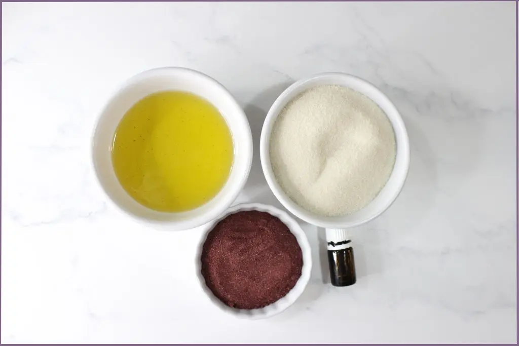 3 bowls with ingredients for sugar scrub - sugar, carrier oil, and hibiscus flower powder+ essential oil bottle