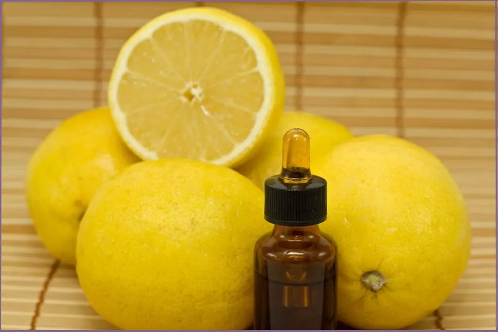 whole and cut lemons and a bottle of essential oil