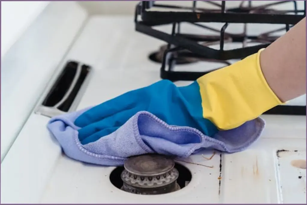 person wearing gloves cleaning stove top