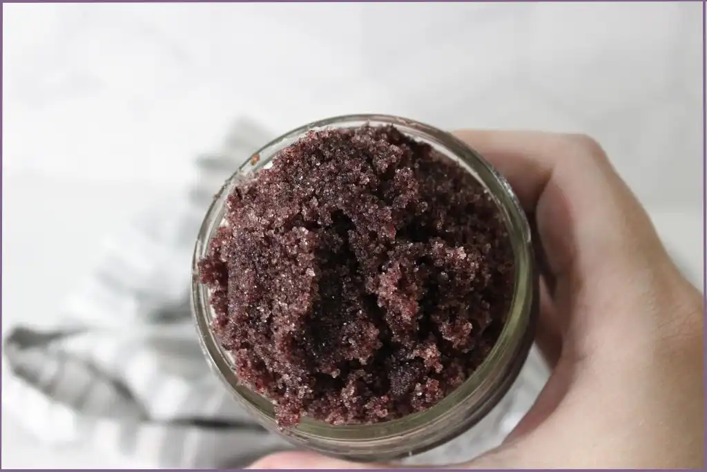 hand holding glass jar with homemade hibiscus sugar scrub