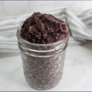 glass jar with homemade hibiscus sugar scrub and striped cloth in background