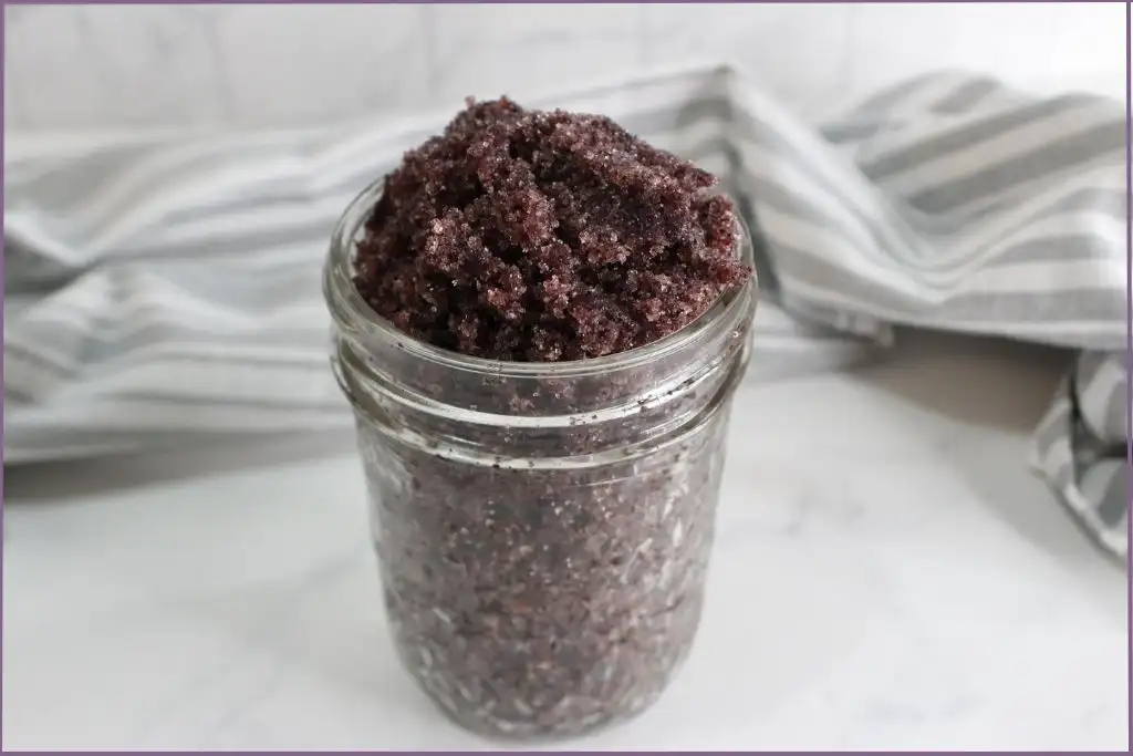 glass jar with homemade hibiscus sugar scrub and striped cloth in background