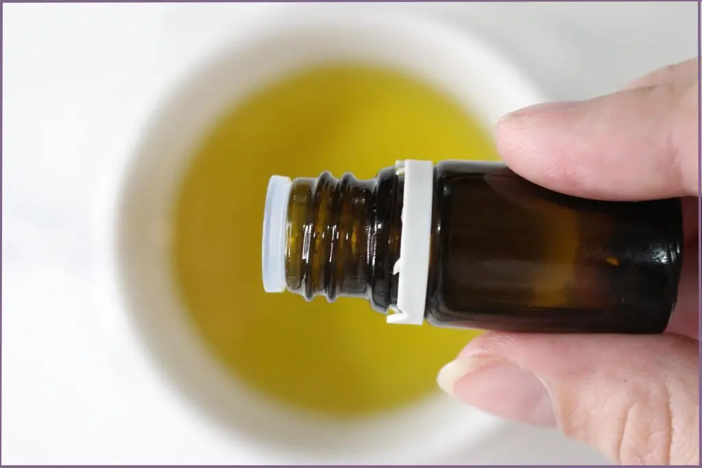 person adding essential oil to a bowl of carrier oil to make sugar scrub