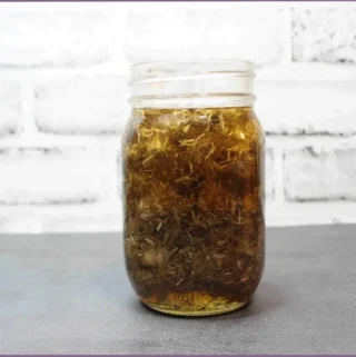 glass jar with arnica flowers steeped in carrier oil