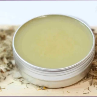 small tin with homemade arnica salve on wooden board