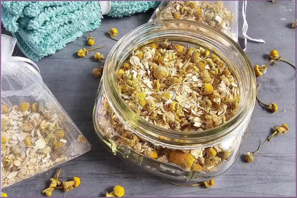 glass bottle and a mesh bag filled with chamomile and oatmeal for homemade herbal bath tea bags