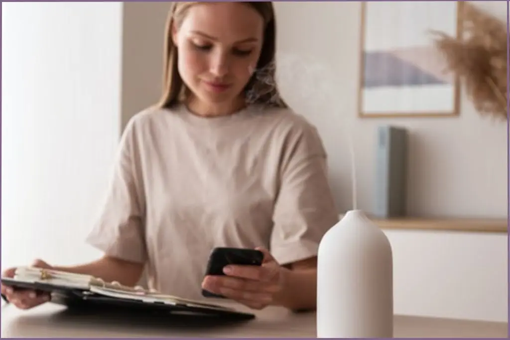 lady scrolling through phone with aromatherapy diffuser on table