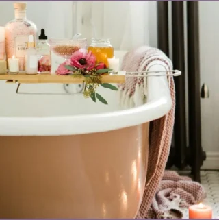 bath tray with candles, bath oil, and soap on a bath tub with candles on the floor