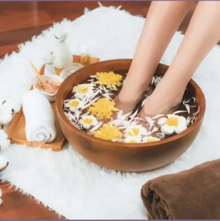 feet in a basin with water set on a towel in spa setting - relaxing Epsom salt foot soak