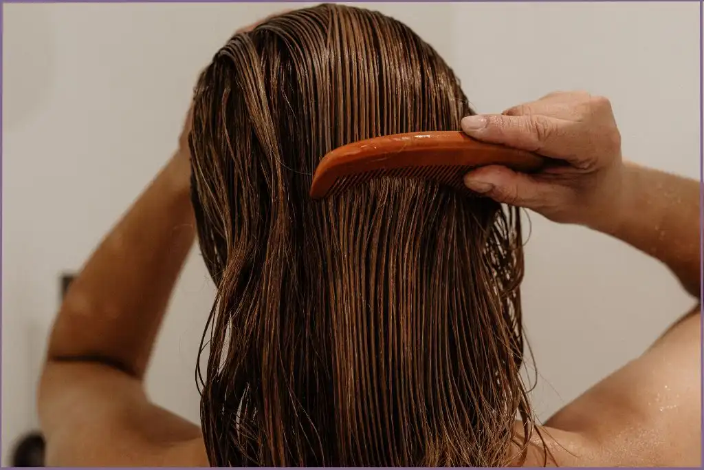 Lady combing damp hair in the bath - Benefits of using essential oils in hair care