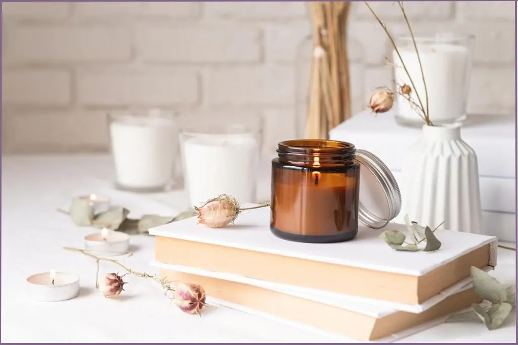 Lighted aromatherapy candle in a brown glass jar in a cozy ambiance