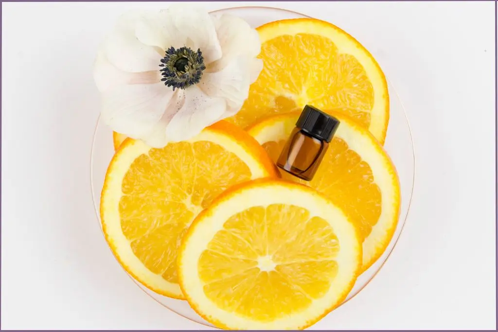 small bottle of summer essential oil lying on top of orange slices