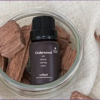 bottle of cedarwood essential oil lying on top of cedarwood chips