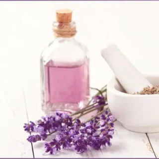 bottle of lavender hydrosol with lavender flowers next to a white pestle and mortar