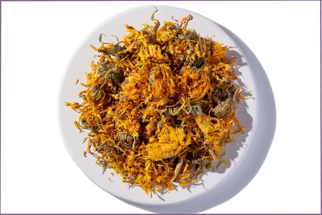 dried calendula flowers in a white plate to make calendula infused oil