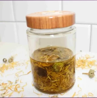 Calendula flowers infused in carrier oil in a glass bottle - how to make calendula oil at home