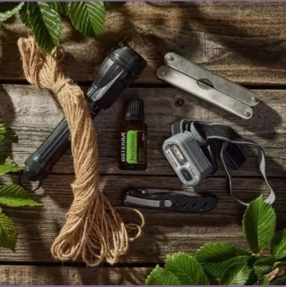 essential oil bottle, penknife, and torch on wooden table outdoors