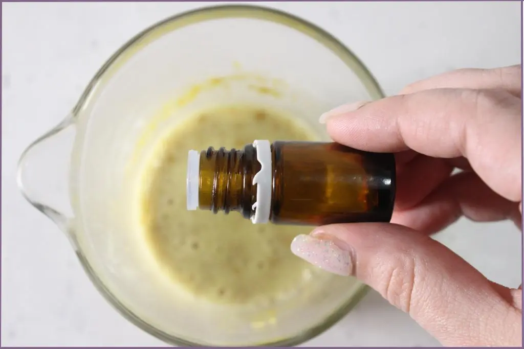 hand pouring essential oil into the melted soap base to make pumpkin spice soap