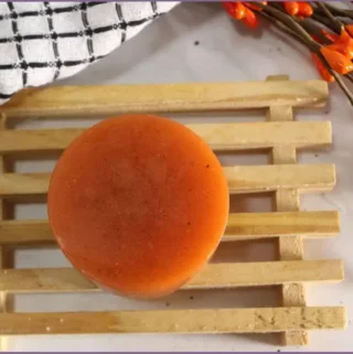 wooden stand with round orange colored homemade pumpkin spice melt and pour soap