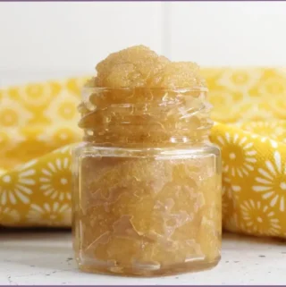 Homemade honey lip scrub with essential oils in a small glass bottle