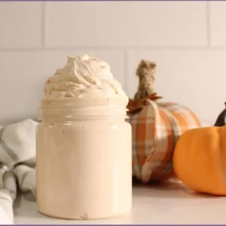jar filled with homemade pumpkin spice whipped body butter in front of a fabric pumpkin