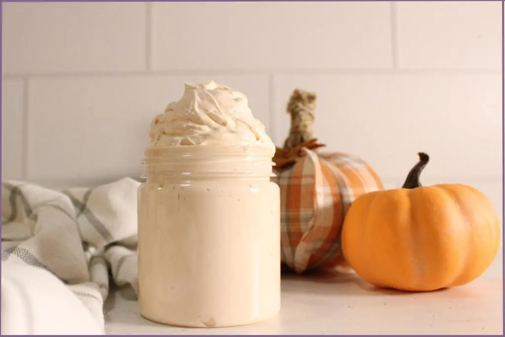 jar filled with homemade pumpkin spice whipped body butter in front of a fabric pumpkin