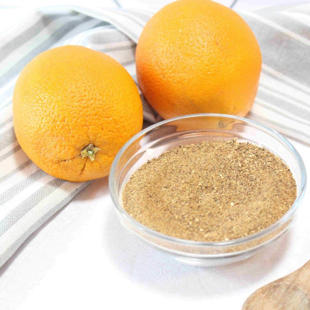 2 oranges and a bowl of orange peel powder with ideas for how to use