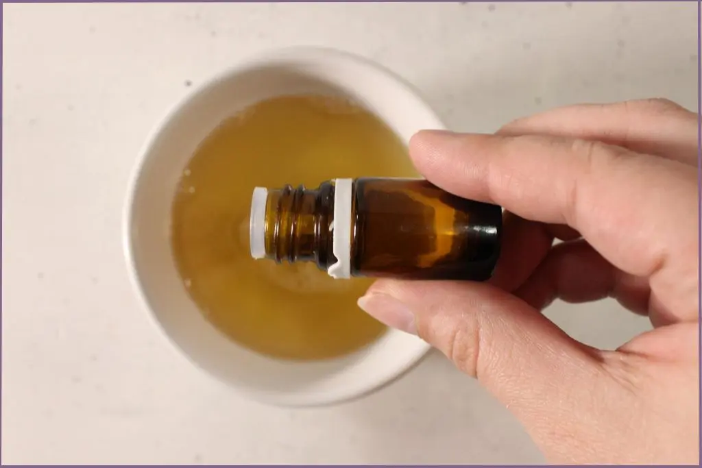 hand pouring essential oil into hand soap mix to scent homemade fall foaming hand soap