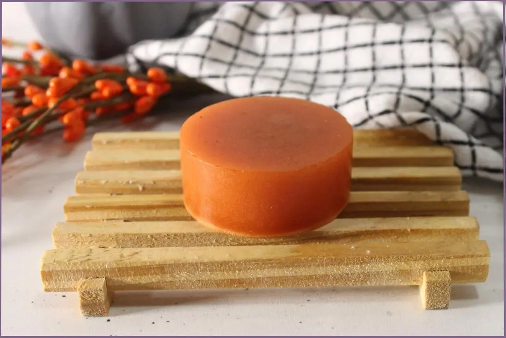 wooden stand with round orange colored homemade pumpkin spice melt and pour soap