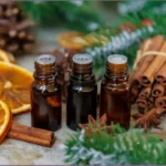 3 bottles of Christmas essential oils surrounded by cinnamon sticks, citrus slices, and fir needles
