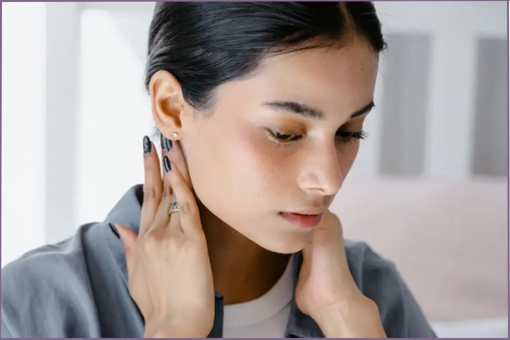 lady dabbing essential oil behind her ears which are good pulse points for essential oils