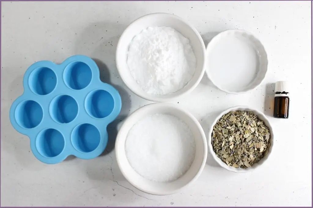 Ingredients for making aromatherapy shower steamers - silicone mold, bowls with Epsom salt, baking soda, eucalyptus leaves and lavender flowers, water