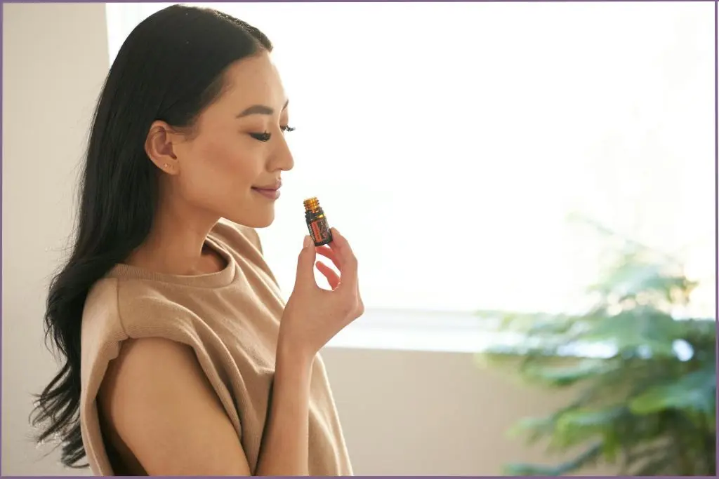 lady inhaling the aroma of essential oil from the bottle