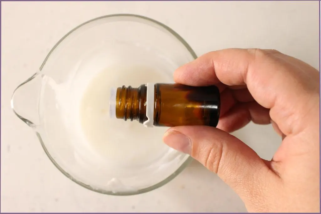 Hand pouring essential oil to melted base for DIY pumpkin spice sugar scrub bars
