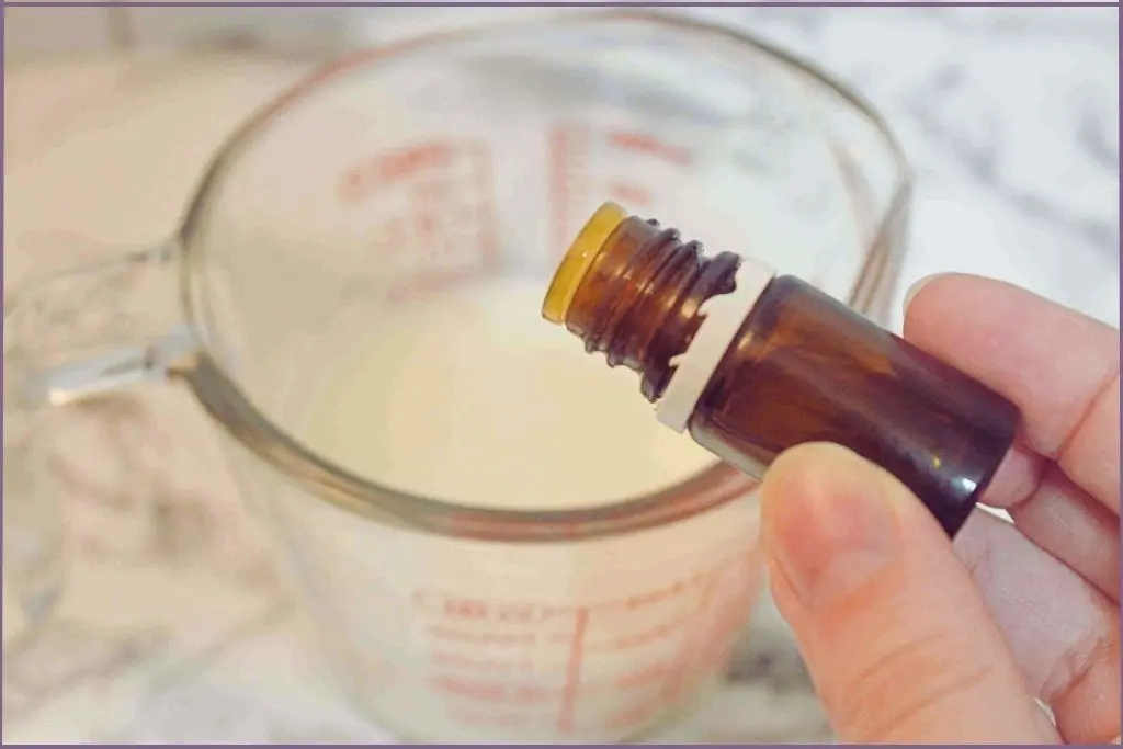 hand pouring essential oil into soap base to scent homemade Christmas soaps