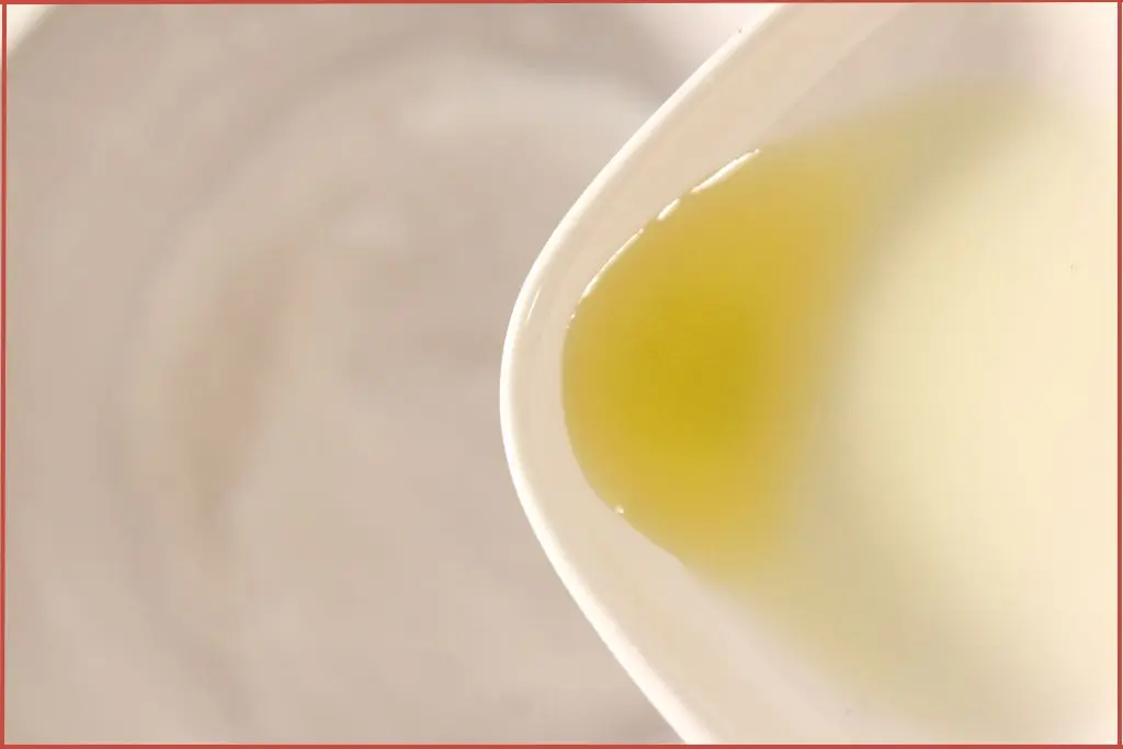 Pouring essential oil and carrier oil into a bowl with dry ingredients for making bath bombs.